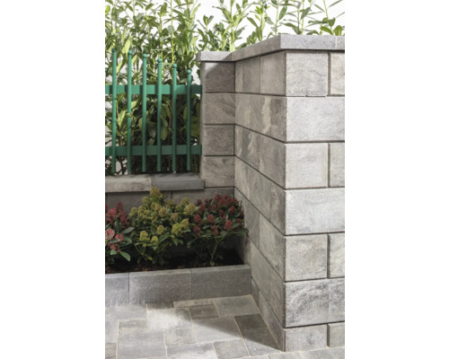 Detailansicht einer Gartenmauer aus Betonsteinen mit Zaun und Bepflanzung