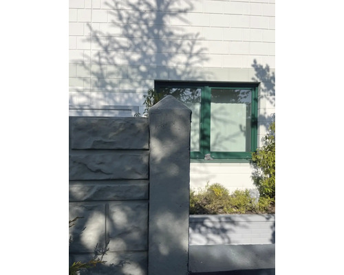 Betonzaunpfosten vor Hausfassade mit Fenster