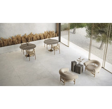 Heller Raum mit Tischen, Stühlen und Steinfliesen