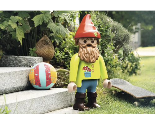 Spielzeugfigur eines Gartenzwergs mit Bart, Mütze und Dekorationen im Garten