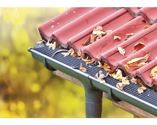 Dachrinne mit Laubschutzgitter und Herbstlaub auf einem Dach
