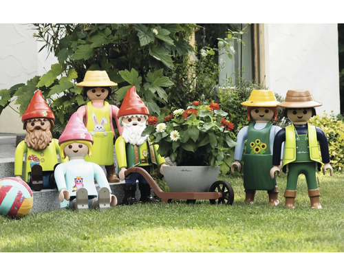 Szene mit Playmobil-Gartenfiguren, darunter Gartenzwerge, ein Paar mit Schubkarre und ein Kind auf einer Rasenfläche