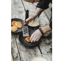 Eine Person wendet Pfannkuchen mit einem Pfannenwender auf einem Teller.