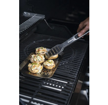 Gefüllte Champignons auf einer Grillplatte mit Grillzange auf einem Grill