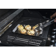 Gefüllte Champignons auf einer Grillplatte mit Grillzange auf einem Grill