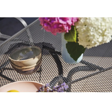 Tischdekoration mit Blumen, Schalen und Geschirr auf einem Gartentisch