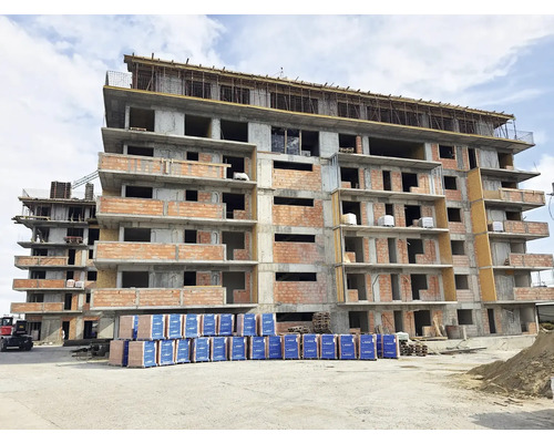 Mehrgeschossiges Gebäude im Rohbau mit Baumaterialien im Aussenbereich