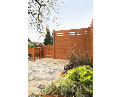 Holzzaun mit Pflanzkasten und gepflastertem Boden im Garten