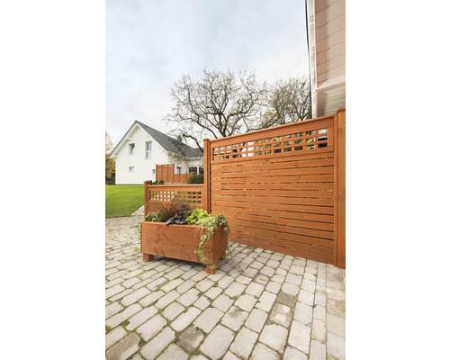 Gartenszene mit Holzzaun, Pflanzkasten und Steinpflaster