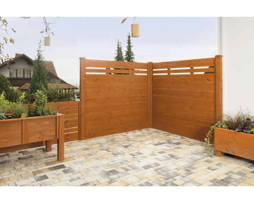 Holzzaun mit Pflanzkästen auf einer gepflasterten Terrasse