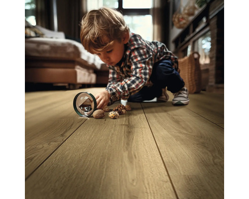 Kind spielt mit Walnüssen auf einem Holzboden im Wohnzimmer