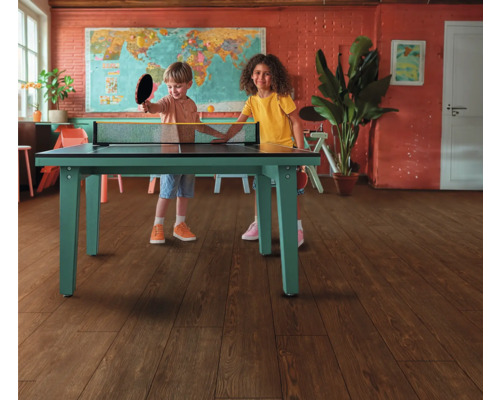 Zwei Kinder spielen Tischtennis im Innenraum auf einem grünen Tischtennistisch.