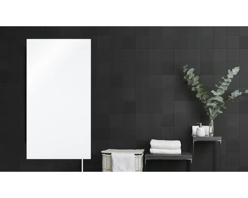 Badezimmer mit Heizkörper, Korb und Handtüchern vor gefliester Wand