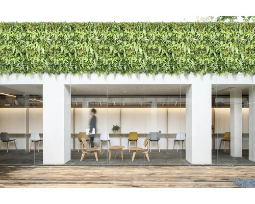 Bürogebäude mit künstlicher grüner Wand, Holzterrasse und modernen Möbeln.