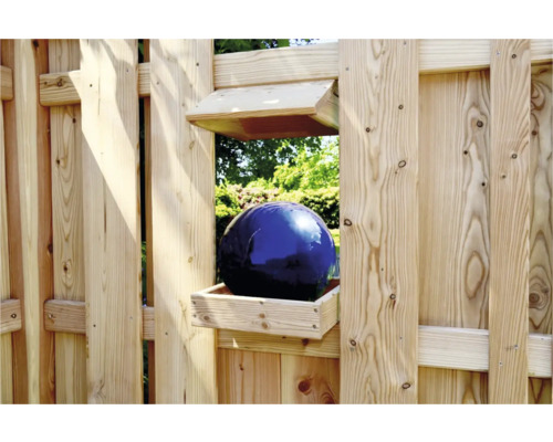 Dekorative blaue Glaskugel in einem Holzkasten auf einem Gartenzaun
