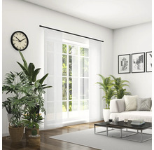 Helles Wohnzimmer mit Sofa, Couchtisch, Zimmerpflanzen, Uhr und Schiebevorhang vor dem Fenster.