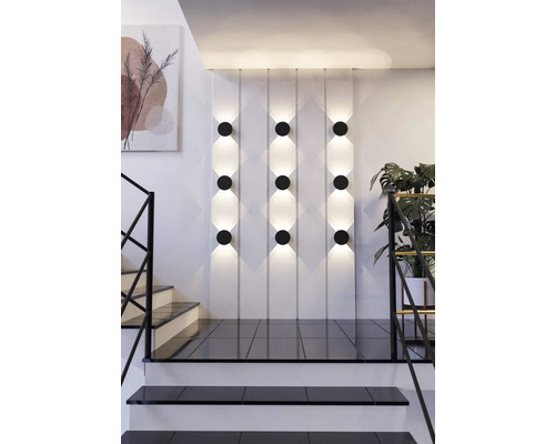 Szene mit Wandleuchten, Treppe und Zimmerpflanze.
