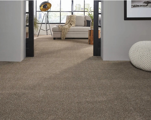 Beiger Teppichboden in einem Wohnzimmer mit heller Couch und dekorativem Pouf