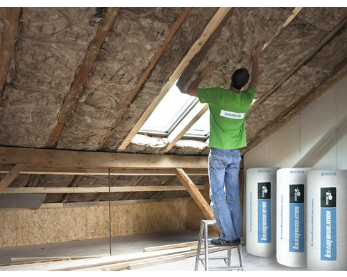 Dachbodenisolierung mit Dämmwolle zwischen Holzbalken, Mann auf einer Leiter bei der Arbeit, Rollen von Knauf Insulation
