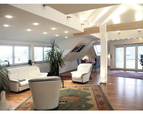 Heller Wohnraum mit Sofa, Sessel, Zimmerpflanzen und Teppich