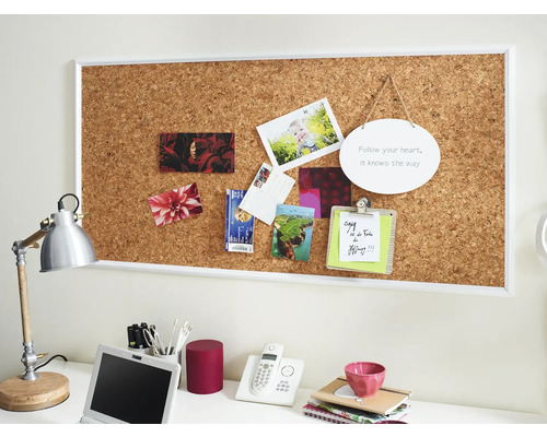 Büroarbeitsplatz mit Korktafel, Fotos, Schreibtischlampe und Büromaterialien
