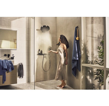 Duschszene mit Frau unter einer Kopfbrause, Badmöbeln und Handtüchern in einem Badezimmer