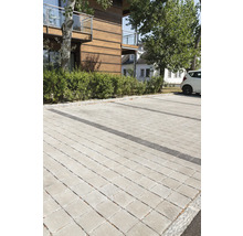 Gepflasterter Parkplatz mit rechteckigen Pflastersteinen vor einem Gebäude.