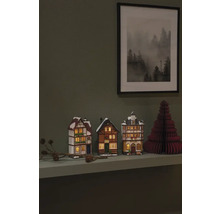Dekorative Miniaturhäuser und ein Papierweihnachtsbaum auf einem Regal mit einem gerahmten Bild an der Wand