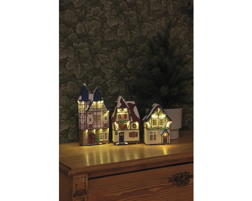 Drei beleuchtete Weihnachtshäuser im Fachwerkstil auf einem Tisch