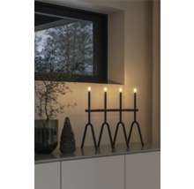 Dekoratives Arrangement mit einer schwarzen Leuchte mit vier Lichtern, einer kleinen Tanne und einem dekorativen Zweig in einem Interieur.