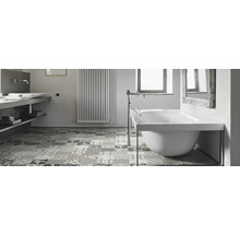 Badezimmer mit Badewanne, Waschbecken, Heizkörper und gemusterten Bodenfliesen