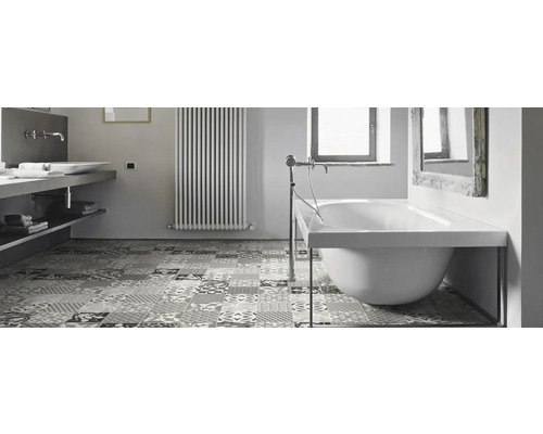 Badezimmer mit Badewanne, Waschbecken, Heizkörper und gemusterten Bodenfliesen