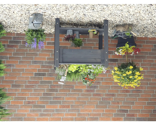 Gartenregal mit Blumen und Pflanzen vor einer Backsteinmauer