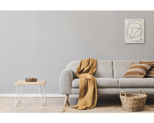 Wohnzimmer mit Sofa, Kissen, Decke, Beistelltisch, Korb und Wandbild