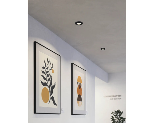 Zwei Deckeneinbaustrahler in einem Ausstellungsraum mit gerahmten Kunstwerken an den Wänden