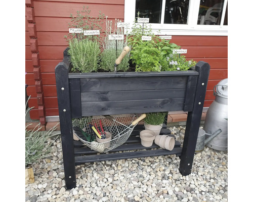 Hochbeet aus Holz mit verschiedenen Kräutern und Gartenzubehör