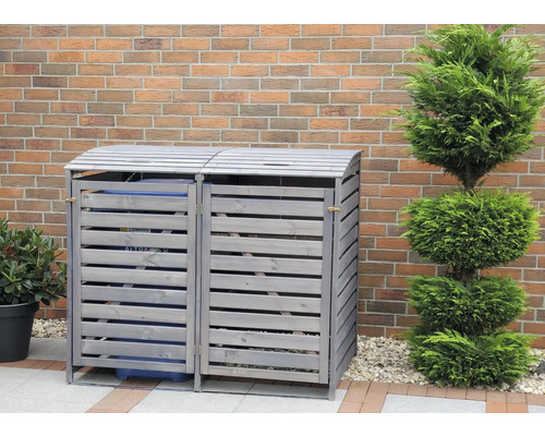 Doppel-Mülltonnenbox aus Holz mit horizontalen Lamellen vor einer Backsteinmauer