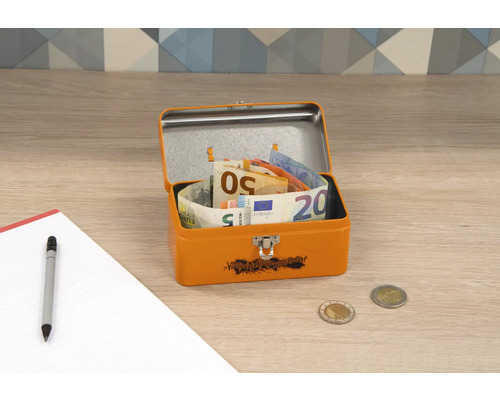 Geöffnete orangefarbene Metallbox mit Euroscheinen, Münzen, Stift und Notizblock auf einem Tisch.