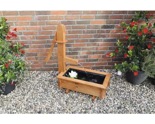 Dekorativer Holzbrunnen mit Wasserpumpe und Seerose im Garten