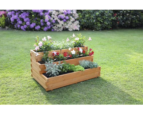 Dreistufiges Hochbeet aus Holz mit verschiedenen Pflanzen im Garten.