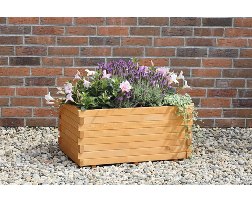 Holzblumenkasten mit Pflanzen vor einer Ziegelmauer