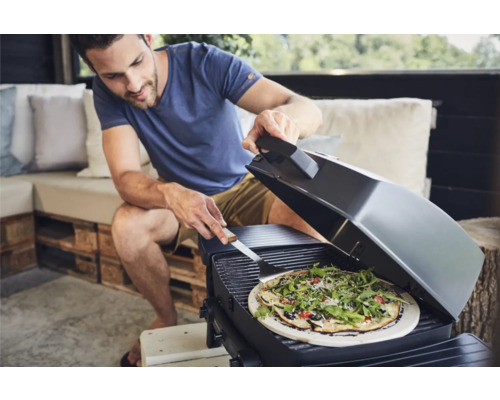 Mann grillt Pizza auf einem Grill im Außenbereich