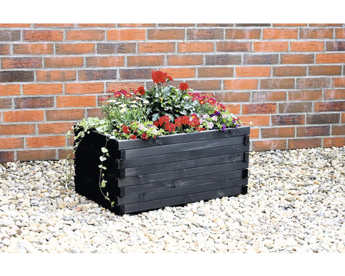 Hochbeet aus Holz mit Blumenschmuck vor einer Backsteinmauer