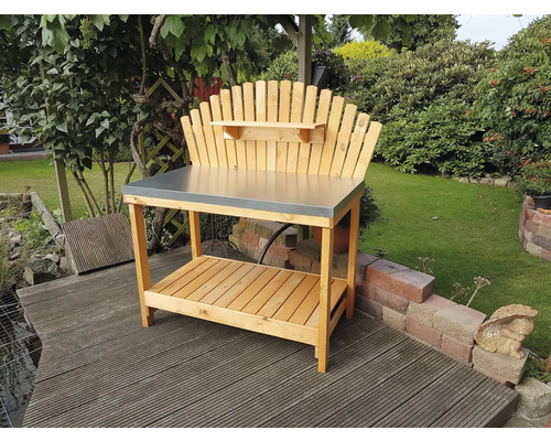 Gartentisch aus Holz mit Metallplatte und Ablage vor Gartenkulisse
