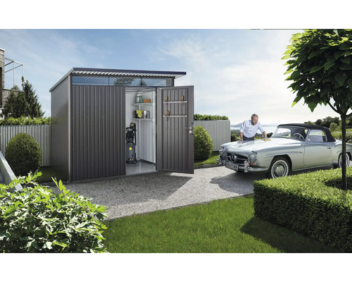 Metall Gerätehaus mit geöffneten Türen, Regalen, Hochdruckreiniger und einem Mann, der ein Auto putzt.