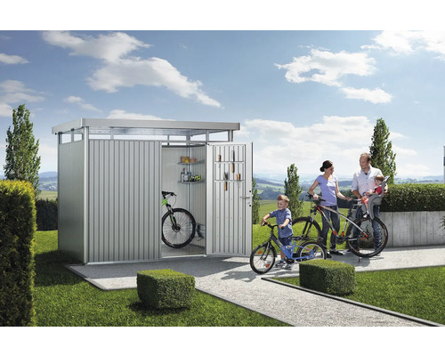 Familie vor einem Metallfahrradschuppen mit Fahrrädern, Regalen und Werkzeugen