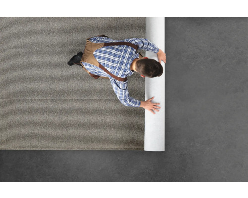 Mann verlegt Teppichboden in einem Raum.