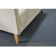 Detailansicht eines Polstermöbels mit Stoffbezug und Holzfüßen auf einem Teppichboden