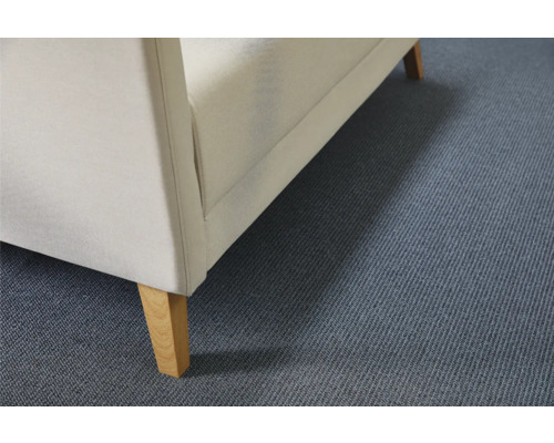 Detailansicht eines Polstermöbels mit Stoffbezug und Holzfüßen auf einem Teppichboden