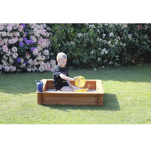 Junge spielt mit Sandspielzeug in einem Sandkasten im Garten.